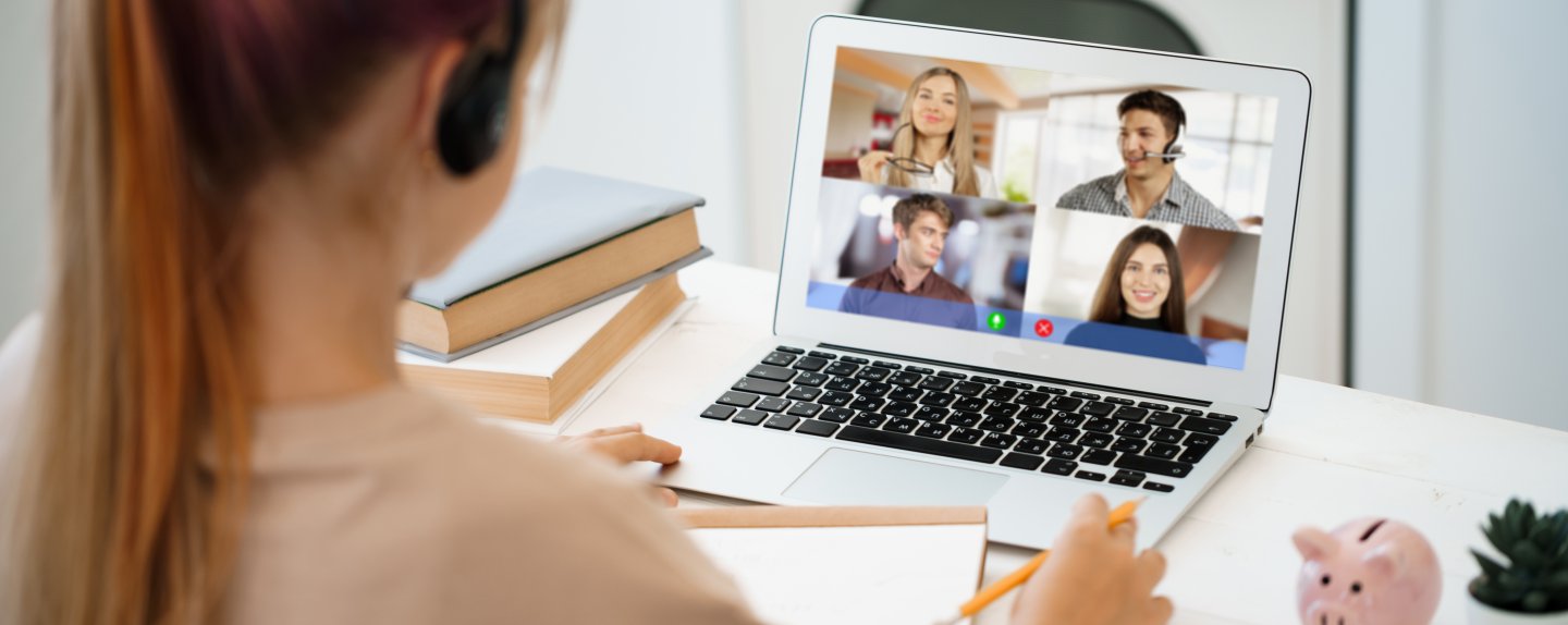 A girl is communicating via video call with classmates on laptop at home